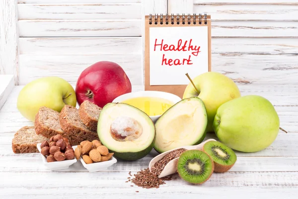 Fuentes saludables de grasa y alimentos saludables que son útiles para el corazón en el fondo de madera con nota Corazón saludable. Concepto de dieta y estilo de vida saludable —  Fotos de Stock
