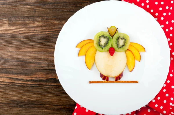 Funny fruits owl for kids breakfast on wooden background. Healthy snacks