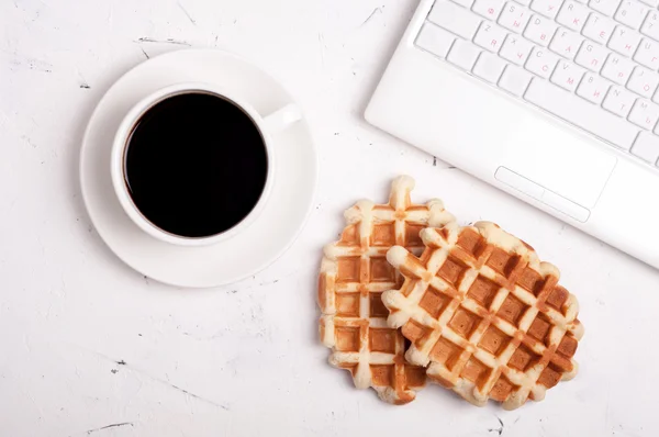 Conceito de pausa para café. Local de trabalho. Mesa de mesa com laptop, xícara de café e waffles no fundo claro com copyspace — Fotografia de Stock