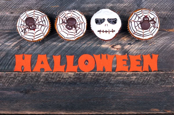 Halloween-Hintergrund. Lustige Kürbismuffins mit Spinnen und Totenkopf zur Halloween-Party auf altem rustikalen Holztisch — Stockfoto