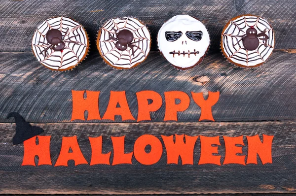 Halloween background. Funny pumpkin cupcakes with spiders and scull for halloween party on old rustic wooden table