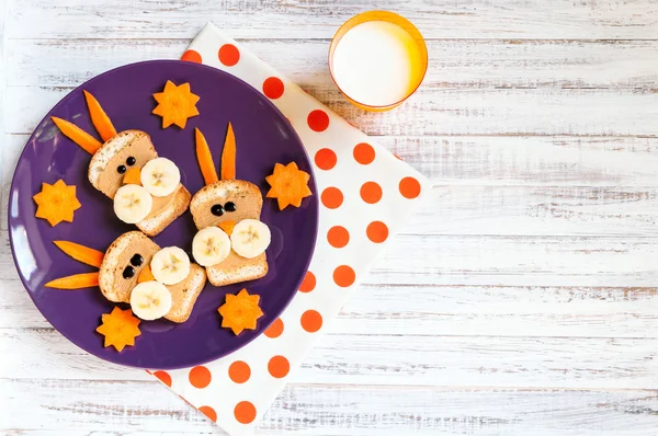 Frukost för barn med smörgåsar och mjölk. Rolig kanin möta smörgåsar med jordnötssmör, banan och morötter — Stockfoto