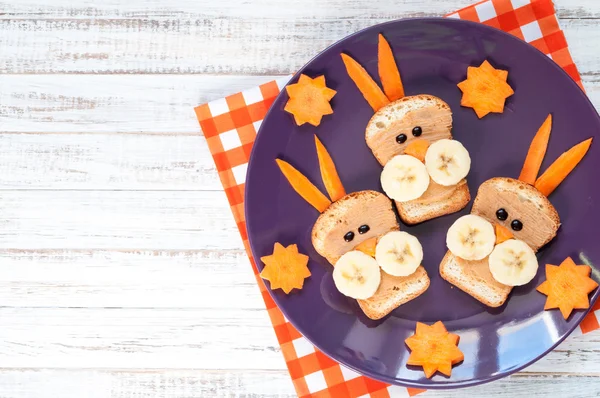 Children's breakfast - funny rabbit face sandwiches with peanut butter, banana and carrots