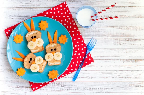 Śniadanie dla dzieci z Kanapki i mleko. Zabawny królik twarz Kanapki z masłem orzechowym, banany i marchewka — Zdjęcie stockowe