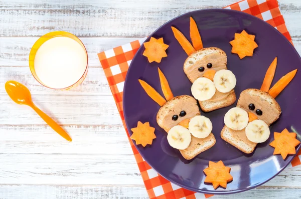 Kinderfrühstück mit Sandwiches und Milch. lustige Hasengesicht-Sandwiches mit Erdnussbutter, Banane und Karotten — Stockfoto