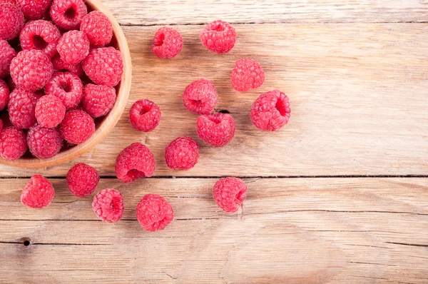 Fresh ripe raspberries in a bowl closeup on old wooden table. Summer berries background — Stock Photo, Image