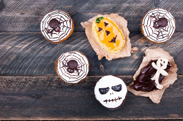 Halloween background. Funny pumpkin muffins with spiders, ghost and scull for halloween party on old rustic wooden table. Copy space