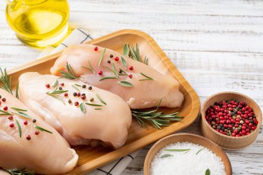 Beyaz ahşap masada baharatlı sebzeli tavuk filetosu. Pişirmek için malzemeli tavuk eti.