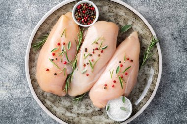 Gri beton masada baharatlı ve otlu tavuk filetosu. Tavuk beyazı et pişiriyorum. Üst görünüm