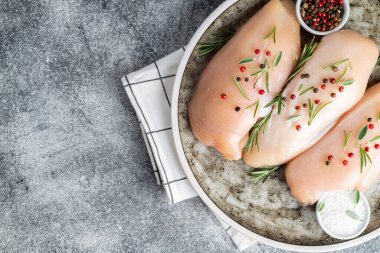 Çiğ tavuk göğsü, baharat ve bitkilerle gri beton masa, pişirmek için malzemeli tavuk eti. Üst görünüm