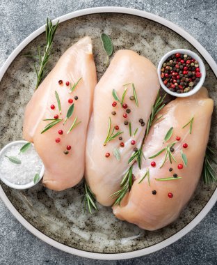 Gri masa üzerinde baharatlı sebzeli tavuk filetosu. Pişirmek için malzemeli tavuk eti. Üst görünüm