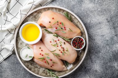 Gri masa üzerinde baharatlı sebzeli tavuk filetosu. Pişirmek için malzemeli tavuk eti. Üst görünüm