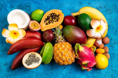 Taze tropikal meyve düzlüğü. Mavi yaz tropik arka planında farklı egzotik meyveler. Taze meyve arka planı. Seyahat ve tatil. Sağlıklı yemek, diyet, vegan, vejetaryen konsepti. Üst görünüm