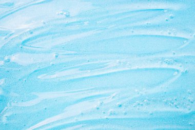 Mavi üzerine sıvı jel kozmetik. Mavi jel ya da dezenfektan. Yüz temizleme için şeffaf jel deseni. Cilt bakımı için nemlendirici kozmetik güzellik ürünü. Kuru cilt bakımı için losyon veya serum