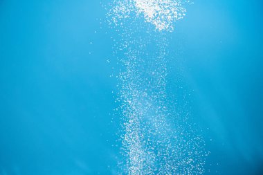 Mavi arka planda beyaz toz sıçraması var. Mavi arka planda un elliyor. Patlayıcı toz beyazı