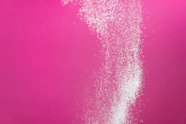 White powder splash isolated on pink background. Flour sifting on a pink background. Explosive powder white