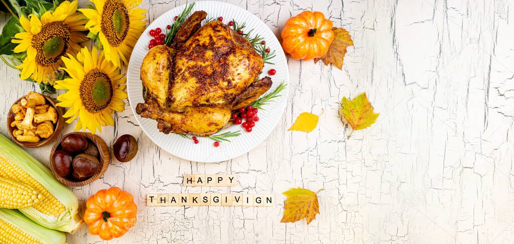 Cooked chicken for Thanksgiving Day. Roasted whole chicken or turkey with autumnal vegetables and fruits for thanksgiving on wooden table. Banner format with copy space