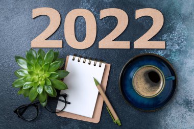 2022 sayılı yeni yıl kararları masada. 2022 gol, açık defter, kahve fincanı, gözlük, mavi masaya sulu bitki. Hedefler, plan, strateji, eylem, fikir konsepti. Yeni Yıl 2022, kopyalama alanı