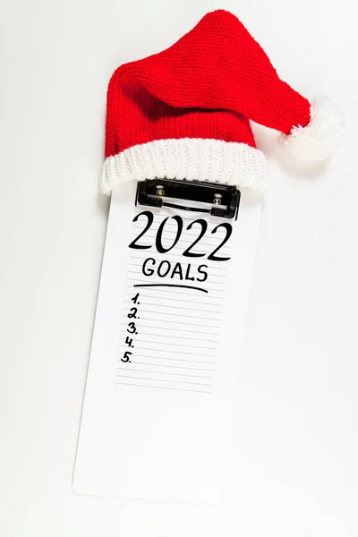 机の上の新年の目標2022 白を背景にノートとサンタの帽子で2022の解像度 アイデアの概念 スペースのコピー — ストック写真