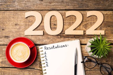 2022 sayılı yeni yıl kararları masada. 2022 karar, açık defter, kahve fincanı, tahta arka planda gözlük. Hedefler, plan, strateji, eylem, fikir konsepti. Yeni Yıl 2022, kopyalama alanı