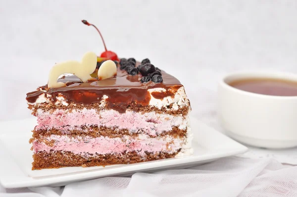 Pezzo di torta di bacche e una tazza di tè nero su uno sfondo bianco — Foto Stock