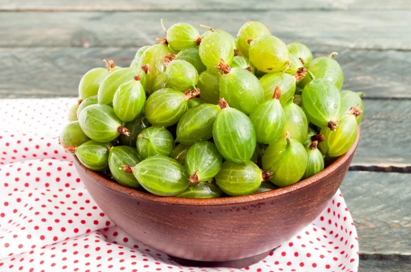 Fresh green gooseberries in a ceramic bowl on a napkin textile. — Stock Photo, Image