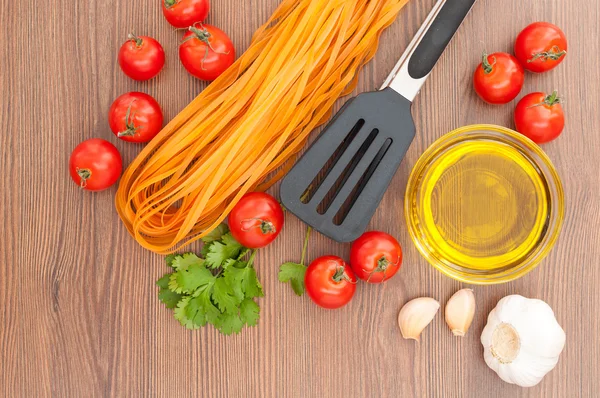 Tomates cereja, massas, azeite, alho, ervas e pinças de macarrão — Fotografia de Stock