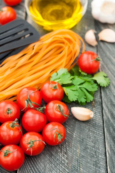 Cherry tomatoes, pasta, olive oil, garlic, herbs and pasta tongs — Stock Photo, Image