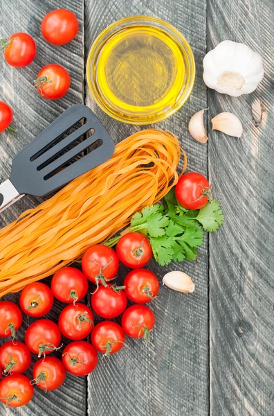 Cherry tomatoes, pasta, olive oil, garlic, herbs and pasta tongs — Stock Photo, Image