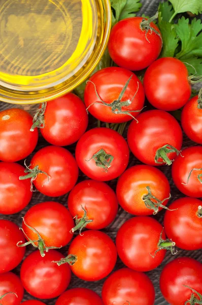 Черри помидоры, оливковое масло и травы на деревянном фоне. Овощ — стоковое фото