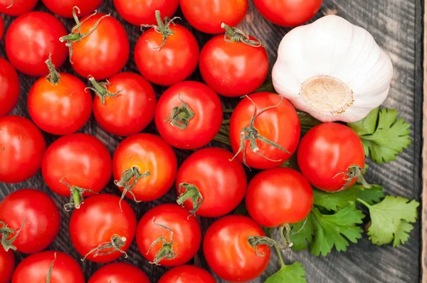 Cherry Tomaten, knoflook en kruiden op een houten achtergrond. Rustieke — Stockfoto
