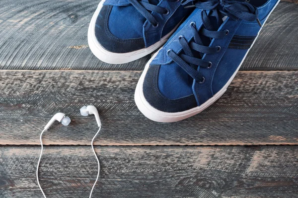 Sneakers and earphones on old wooden background — Stockfoto