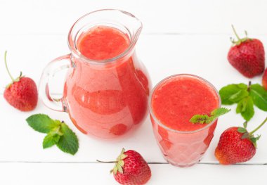Fresh strawberry smoothie with mint on a white wooden background