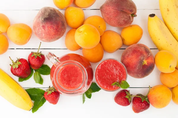 Healthy strawberry banana smoothie with mint in a glass and pitc