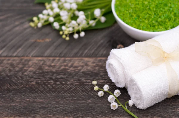 Natural green sea salt and towel for bath and spa on a wooden bo — Stockfoto