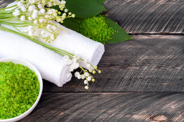 Natural green sea salt and towel for bath and spa on a wooden bo — Stock fotografie