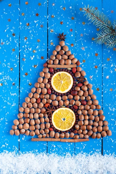 Christmas tree made of nuts and dried fruits on the wooden backg