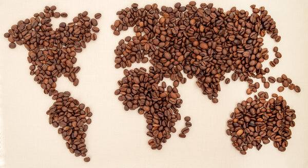 Roasted coffee beans arranged in a world map on textile background