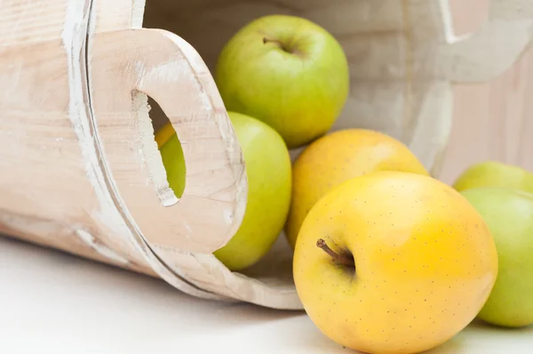 Green and yellow apples in an old wooden bucket — Stock Photo, Image