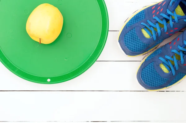 Old sport shoes and dumbbell on a dark wooden background