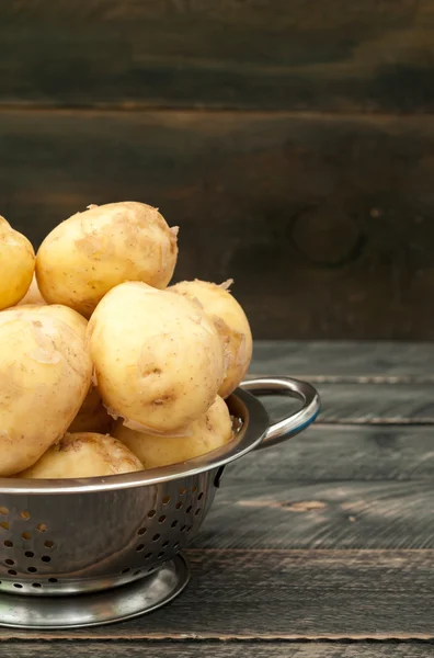 Batata jovem orgânica em uma tigela em uma mesa de madeira . — Fotografia de Stock