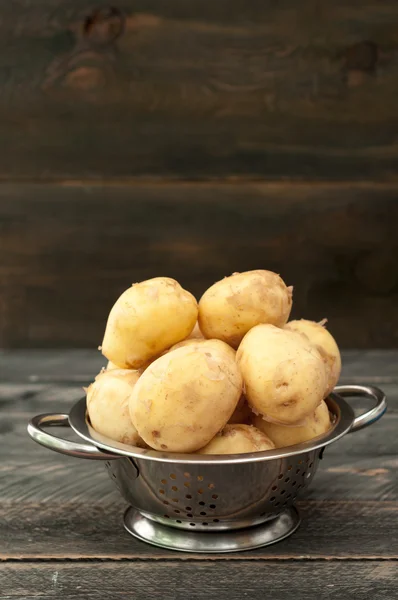 Ekologisk unga potatis i en skål på ett träbord. Selektiv tant — Stockfoto