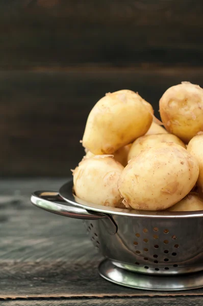Organické mladých brambor v misce na dřevěný stůl. — Stock fotografie
