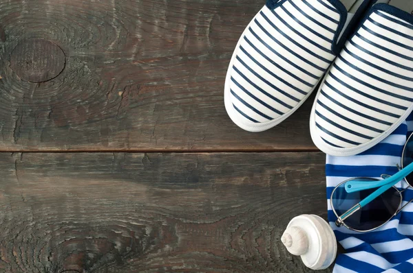 Sea shoes, striped cloth, shell and sunglasses on old wooden bac — Stock Photo, Image