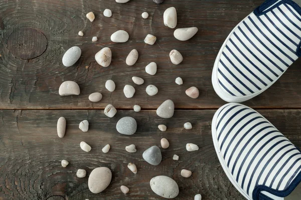 Shoes and stones on old wooden background — Stock Photo, Image