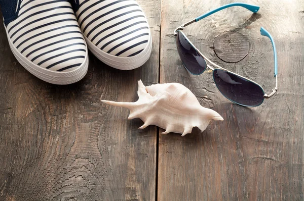 Zapatos de mar y concha y gafas de sol sobre fondo de madera vieja — Foto de Stock