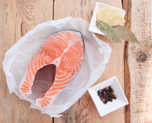 Raw salmon steak red fish and spices on wooden table — Stock Image Raw salmon steak red fish and spices on wooden table Royalty Free Stock Images