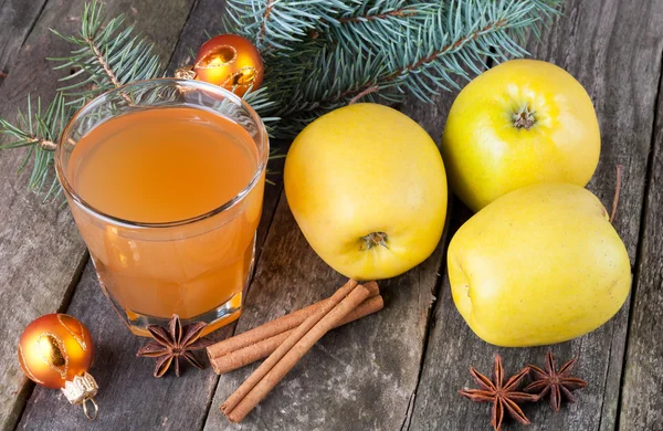 Apple juice in glass, apples, spices and fir on the old wooden b — Stock Photo, Image