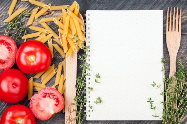 Open sheet cookbook with pattern polka dot, spoon with penne pas — Stock Photo, Image