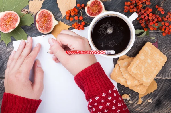 Vrouw handen schrijven op een leeg vel papier op een houten tabl — Stockfoto